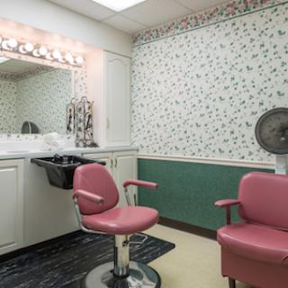 A vintage-style hair salon featuring pink styling chairs and floral wallpaper.