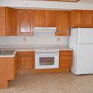 A kitchen with wooden cabinets, a stove, and a refrigerator.