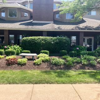 A well-maintained building with lush landscaping under bright sunlight.