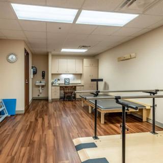 A physical therapy room equipped with parallel bars and rehabilitation equipment.