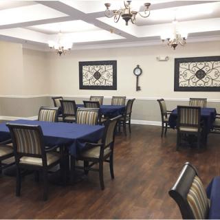 A well-decorated dining room with blue tablecloths, wooden chairs, and elegant chandeliers.