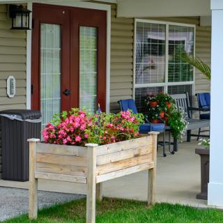 A cozy porch with a wooden planter box filled with vibrant flowers and comfortable patio furniture.