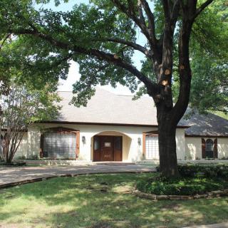 A suburban house with a large tree in the front yard.