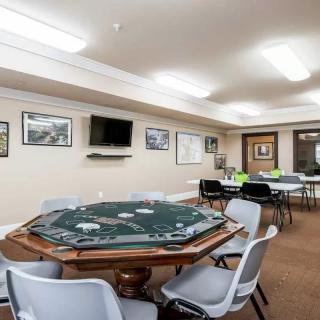 A spacious game room featuring a poker table surrounded by chairs, with decor and a television mounted on the wall.