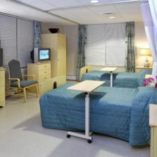 A well-equipped hospital room with two beds and a television.