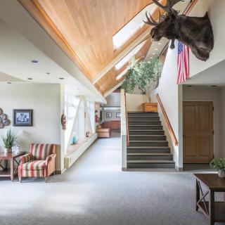 A well-lit lobby area featuring a staircase, wood ceiling, and moose head decor.