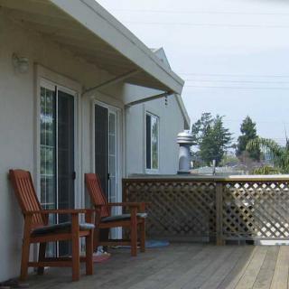 A relaxing outdoor deck with wooden chairs and a view of the neighborhood.