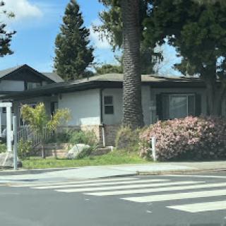 A charming residential house with a well-maintained garden and trees.