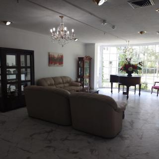 A well-lit living room featuring a comfortable sofa, a grand piano, and elegant decor.