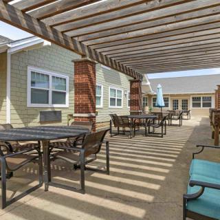 An outdoor patio with a pergola, featuring tables and chairs for seating.
