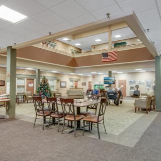 A spacious lobby area with tables and chairs, decorated with warm lighting and decor.
