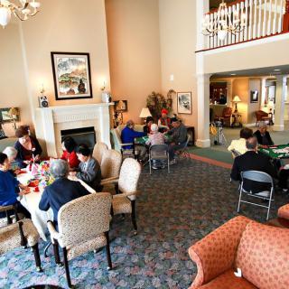 A group of people socializing in a spacious living room with comfortable seating and decor.