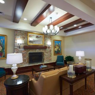 A cozy living room with a fireplace, elegant furniture, and decorative ceiling beams.