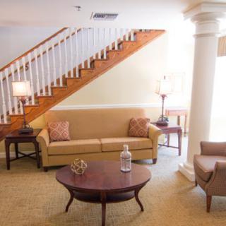 A cozy living room featuring a comfortable sofa, elegant lamps, and a staircase in the backdrop.