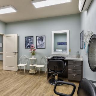 A neatly arranged hair salon interior with chairs, a mirror, and wall decor.