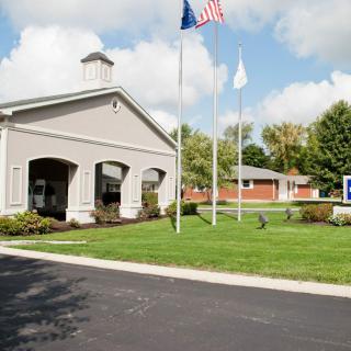 A public building with flags in front, surrounded by a well-maintained lawn on a cloudy day.