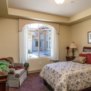 A cozy bedroom with a large window, bed, and comfortable seating.