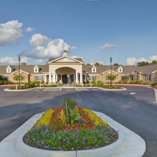 A well-manicured building entrance with vibrant landscaping and a clear sky.
