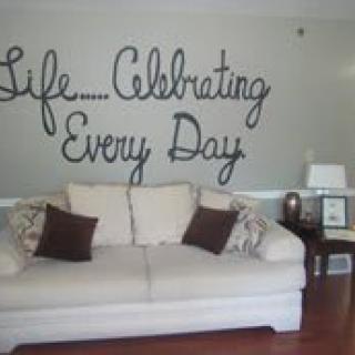 A cozy living room with a motivational quote on the wall: 'Life... Celebrating Every Day'.