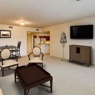 A spacious living room with modern furniture and a flat-screen TV, adjacent to a dining area.