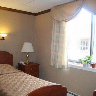 A cozy hotel room featuring a single bed and natural light from a window.