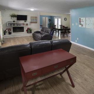 A spacious living room with a couch, table, television, and fireplace.