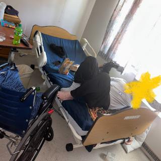 A patient resting in a hospital bed with a wheelchair nearby.