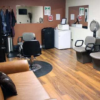 A cozy hair salon interior with styling chairs, mirrors, and a small lounge area.