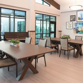 A modern dining area featuring elegant wooden tables and chairs, enhanced by ample natural light from large windows.