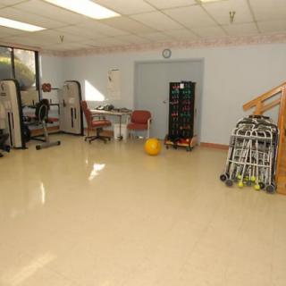 An empty indoor gym space equipped with exercise and rehabilitation equipment.