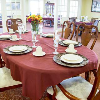 A dining table elegantly set with plates, glasses, and candles, featuring a centerpiece of flowers.