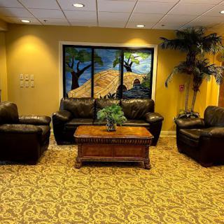 A cozy lobby area with leather seating, a wooden table, and decorative plants.