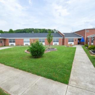 A school courtyard featuring green grass and brick buildings.