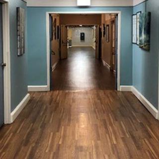 A long, well-lit hallway with wooden floors and blue walls.