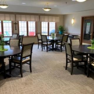 A spacious community dining room with several tables and chairs, featuring large windows and tasteful decor.