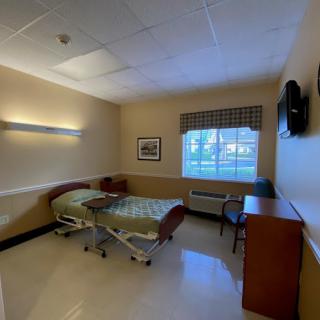 A hospital room with a bed, window, and essential furniture.