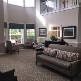 A spacious living room with large windows, comfortable seating, and decorative artwork.