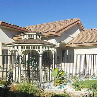 A residential house with a fenced gazebo and landscaped garden.