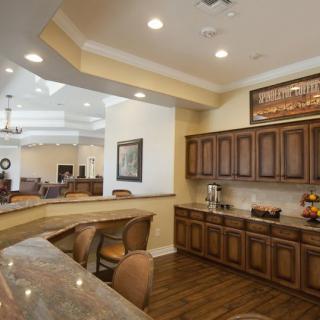 A modern kitchen and dining area with wooden cabinets and elegant lighting.