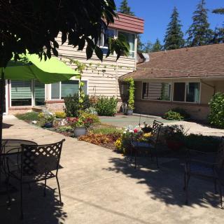 A sunny patio with outdoor furniture surrounded by a well-maintained garden and residential buildings.