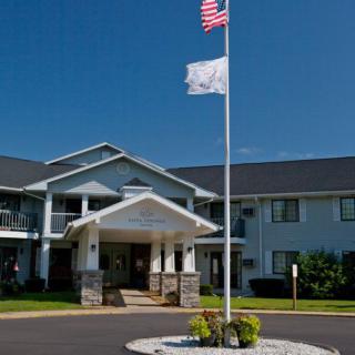 A two-story building with an entrance canopy, featuring American and white flags in front.