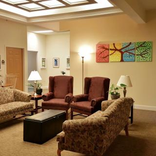 A cozy living room with sofas, chairs, and vibrant artwork on the wall.
