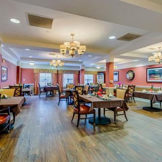 A warm and inviting dining room with elegant chandeliers, neatly arranged tables, and a welcoming atmosphere.