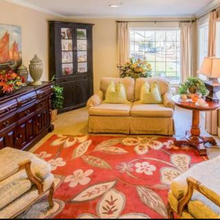 A cozy living room with a red patterned rug, comfortable seating, and elegant decor.