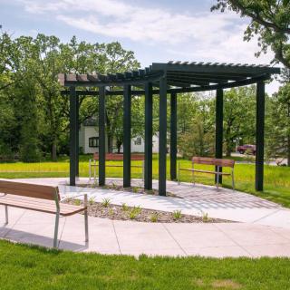 A peaceful park setting featuring a pergola and benches surrounded by greenery.