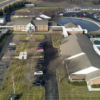 Aerial view of buildings with a parking lot and surrounding landscape.