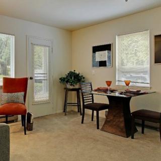 A cozy dining area with a table set for two, featuring modern decor and natural lighting.