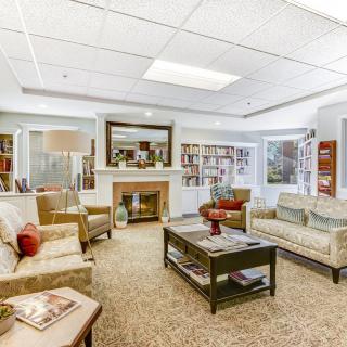 A cozy living room with comfortable sofas and a coffee table, surrounded by bookshelves and decorative elements.