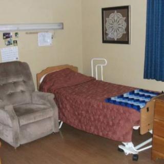 A hospital room with a bed, chair, and curtains.