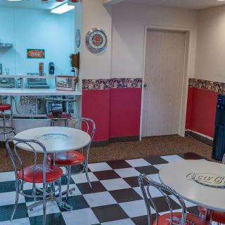 A retro-style diner with checkerboard flooring and vintage decor.